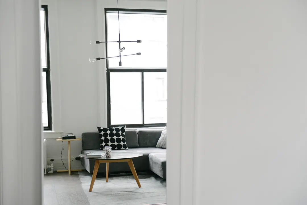 White living room with a grey sofa, a round coffee table and tall windows