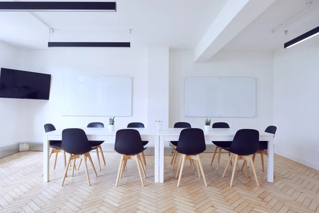 Bright meeting room with a long white table and dark chairs