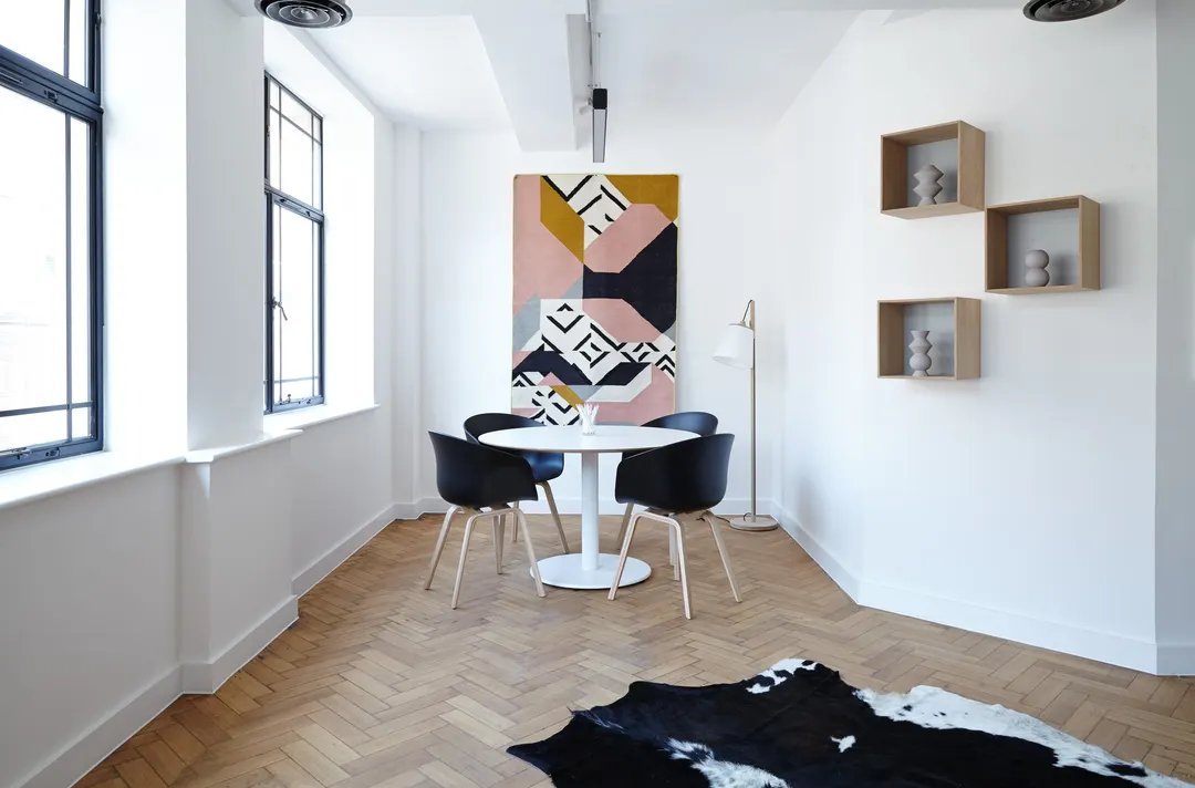 White room with a round table, a patterned artwork and wall shelves