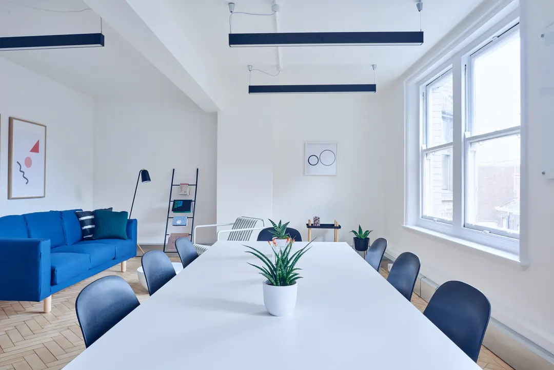 White workroom with a blue sofa and a long table