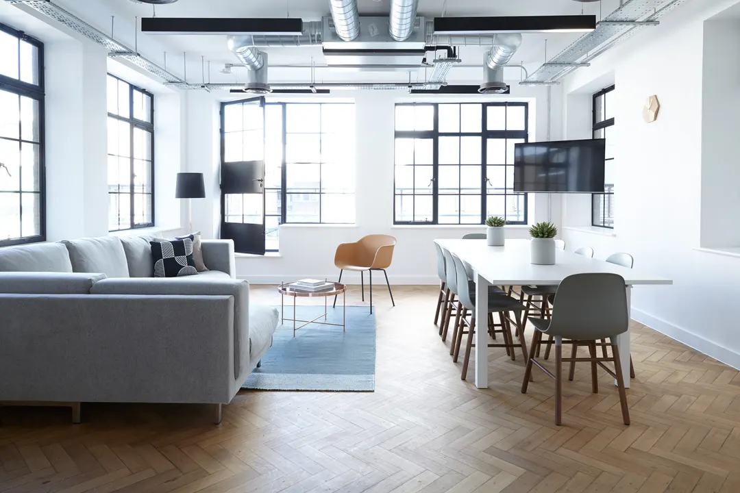Loft lounge with a grey sofa, a dining table and industrial windows